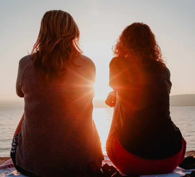 Women sitting facing sunset.